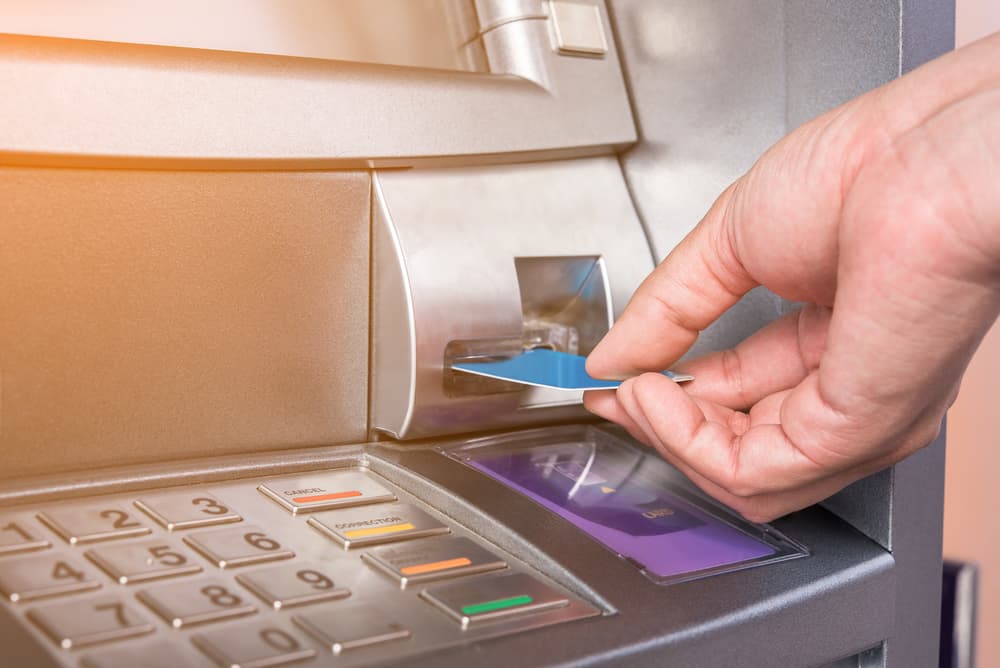 A person inserts a bank card into an ATM, preparing to access their account.