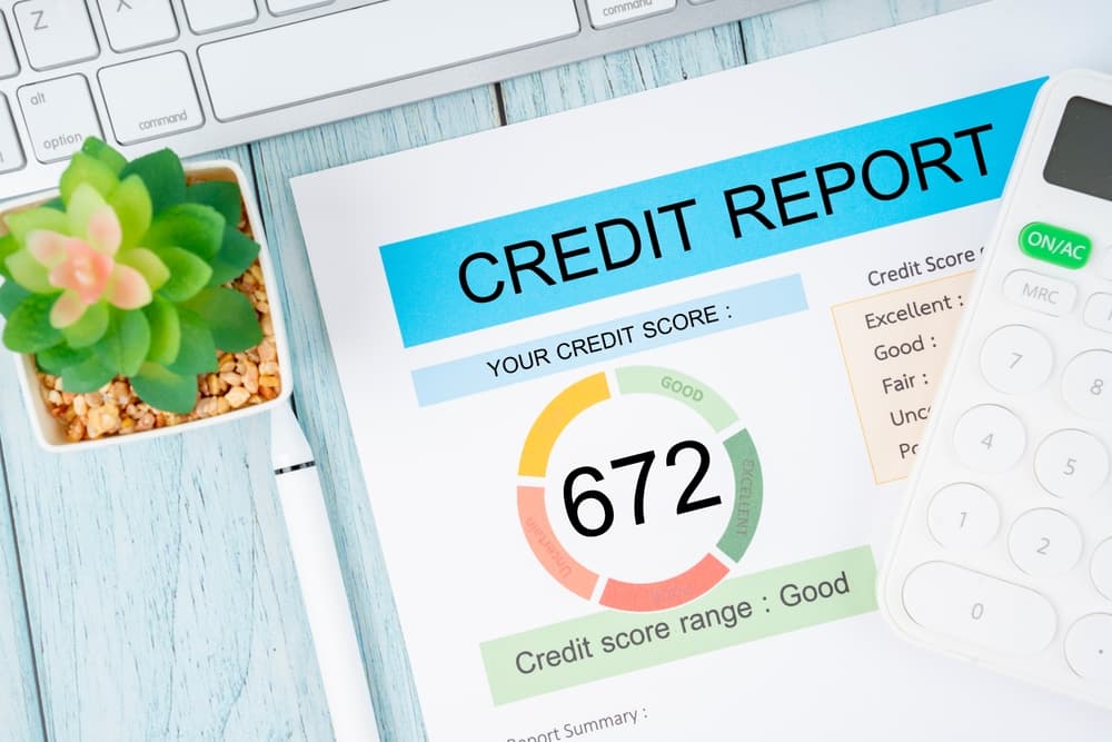 A credit report showing a score of 672 next to a calculator, keyboard, and plant.