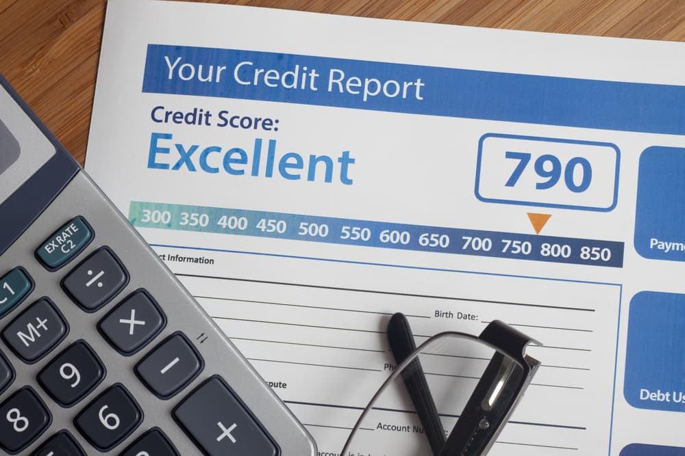 A credit report showing an excellent score of 790 next to a calculator and pen.