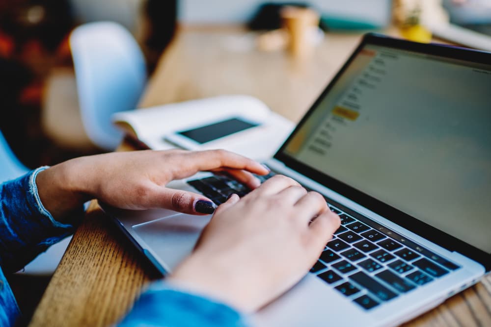 Close-up of woman's hands typing on laptop keyboard, shopping online with wireless internet connection.