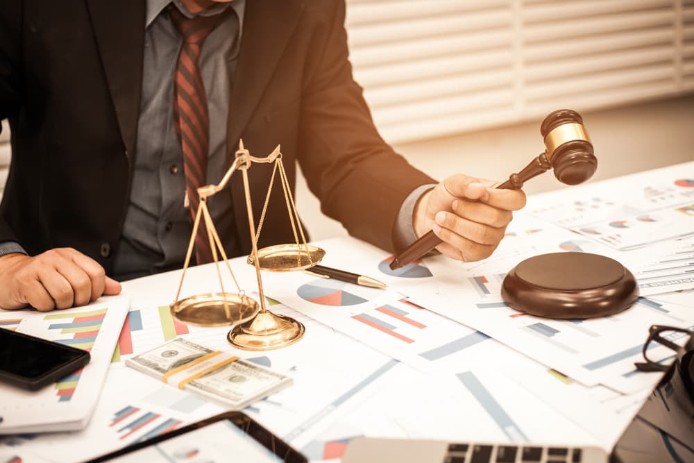 Consumer protection lawyer working at desk with scales of justice and judge gavel in the office.