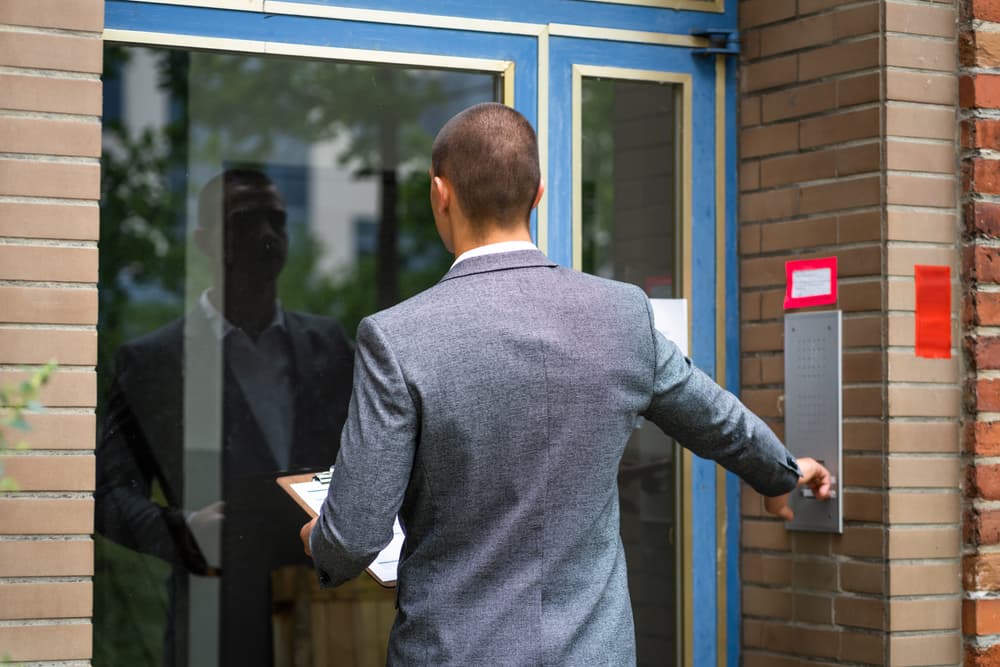 Bailiff ringing doorbell for debt collection, initiating confiscation and seizure.