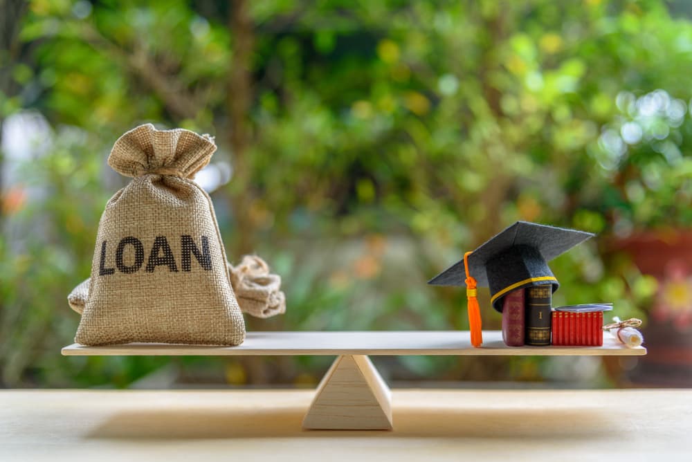 Balancing scale with a loan bag on one side and graduation items on the other.