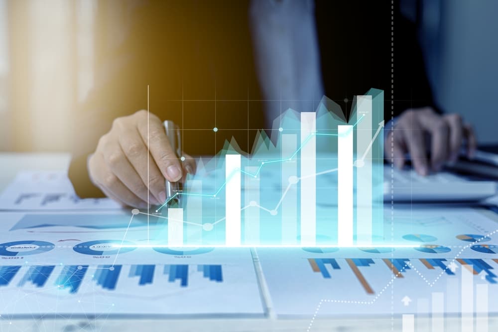 Businessperson analyzing growth charts with digital graph overlay and financial documents.