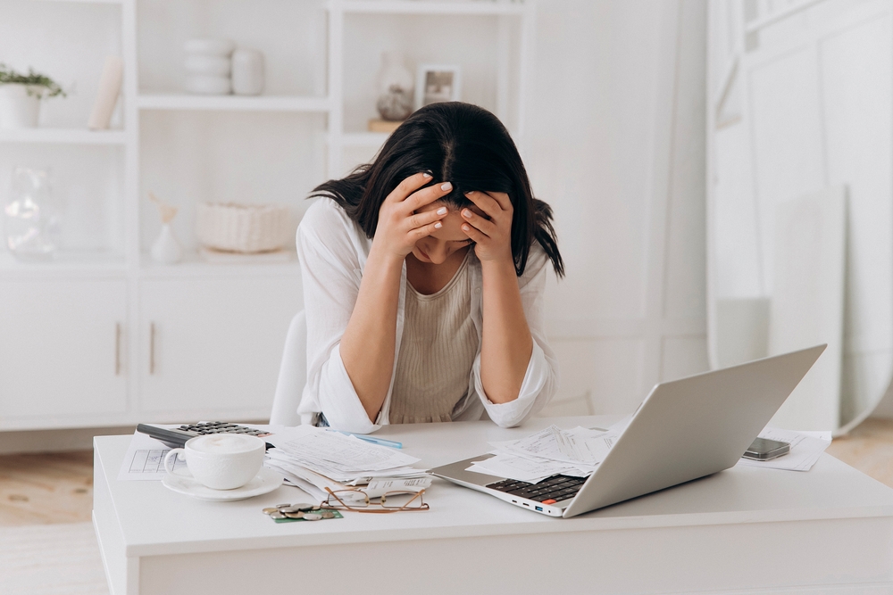 Young woman stressed by financial paperwork, highlighting the cons of debt consolidation like added stress and complexity.