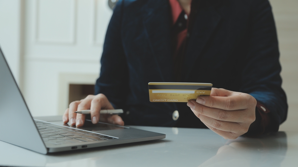 Close-up of a man's hand holding a credit or debit card with a padlock, symbolizing financial transaction security.