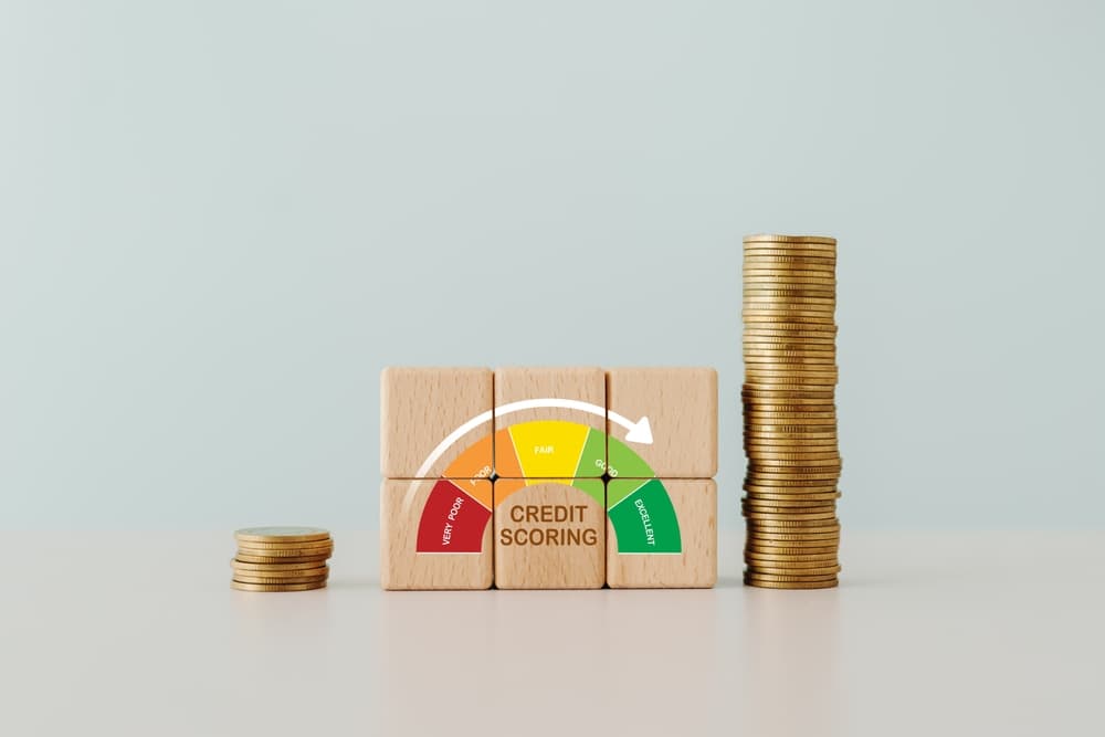 Wooden cube block with 'CREDIT SCORING' text and gauge meter indicator, placed next to a stack of coins.